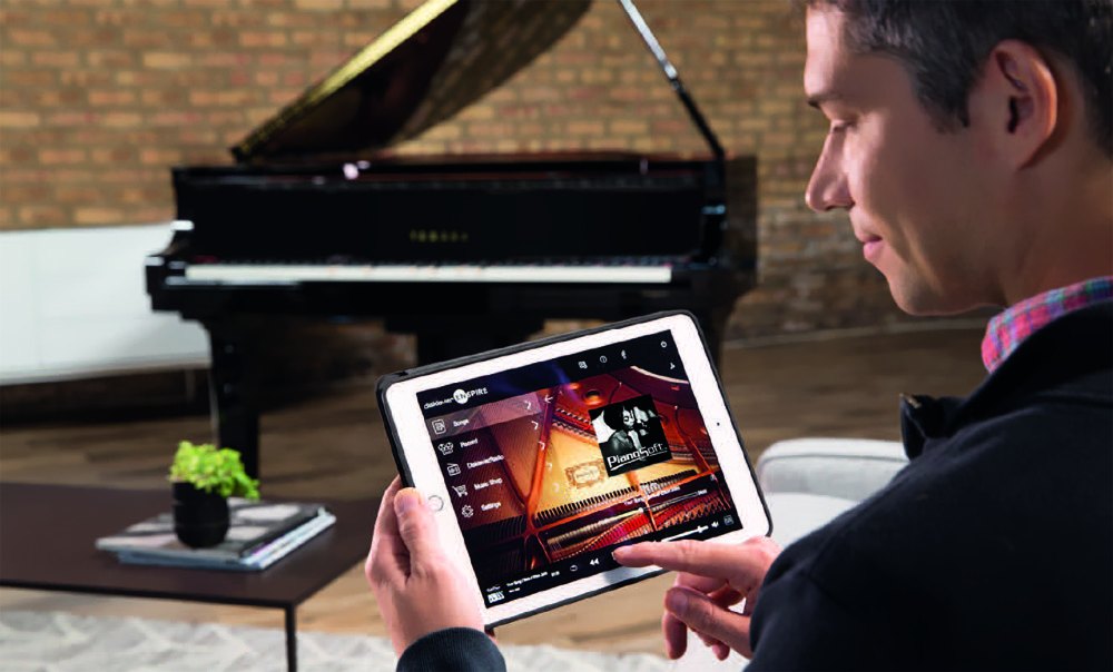 Man using an iPad to remotely control the Disklavier Enspire