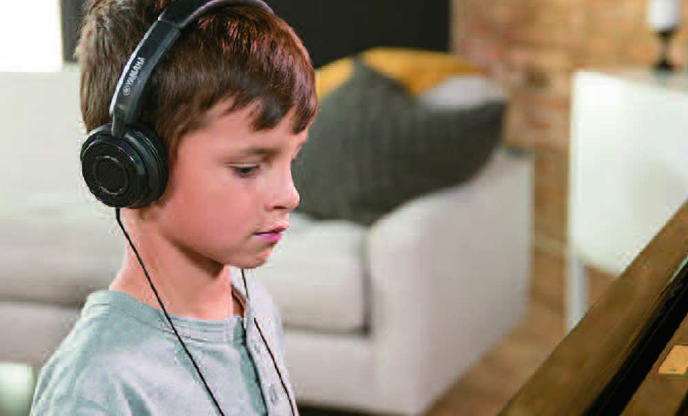 Boy playing Enspire piano silently using headphones