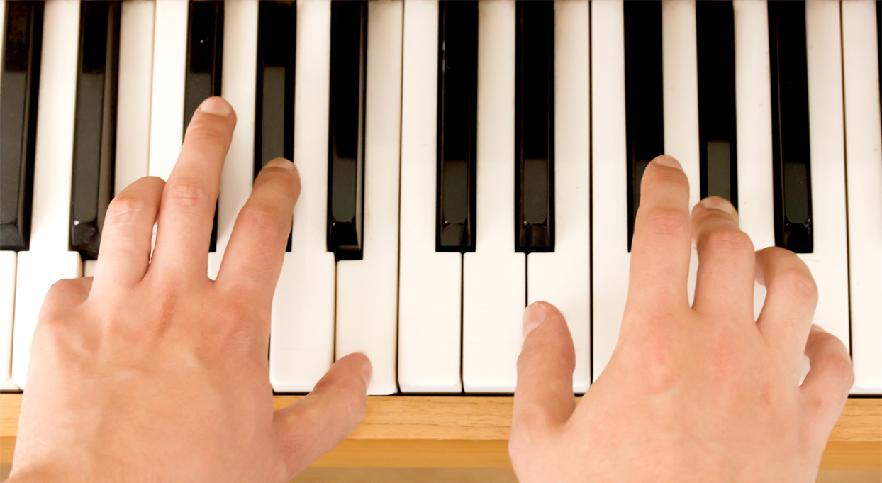 Image of hands playing an acoustic piano