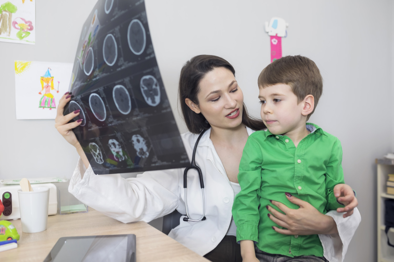 Photo of a doctor showing a young child the images from an MRI scan