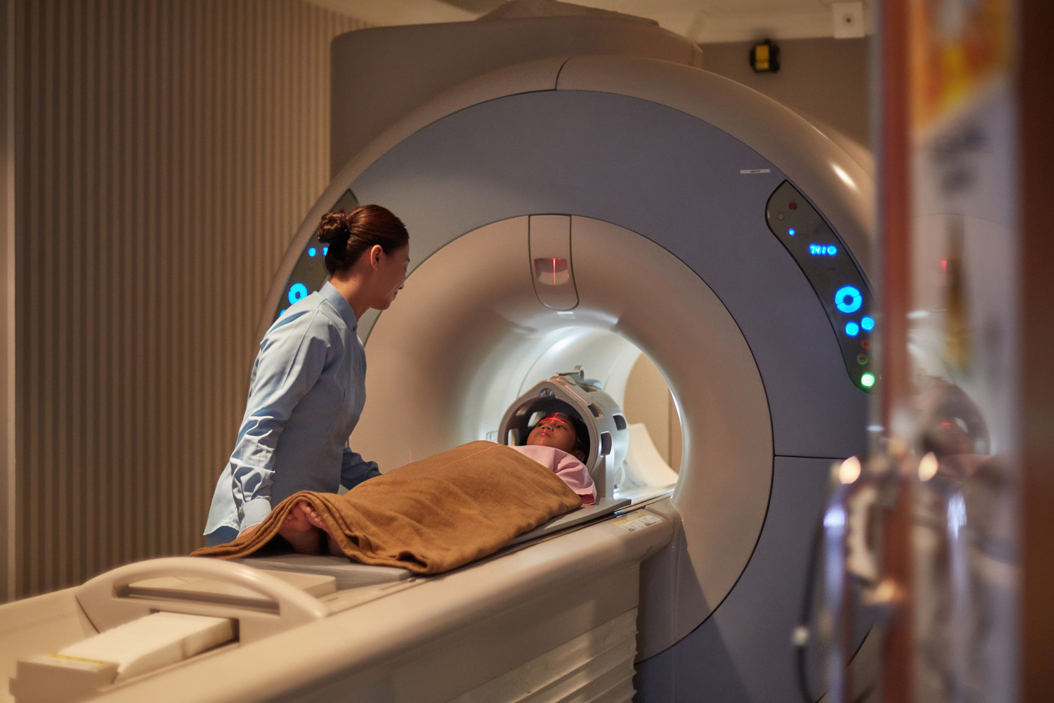 Photo of a young child about to undergo an MRI scan in a hospital, with a nurse helping