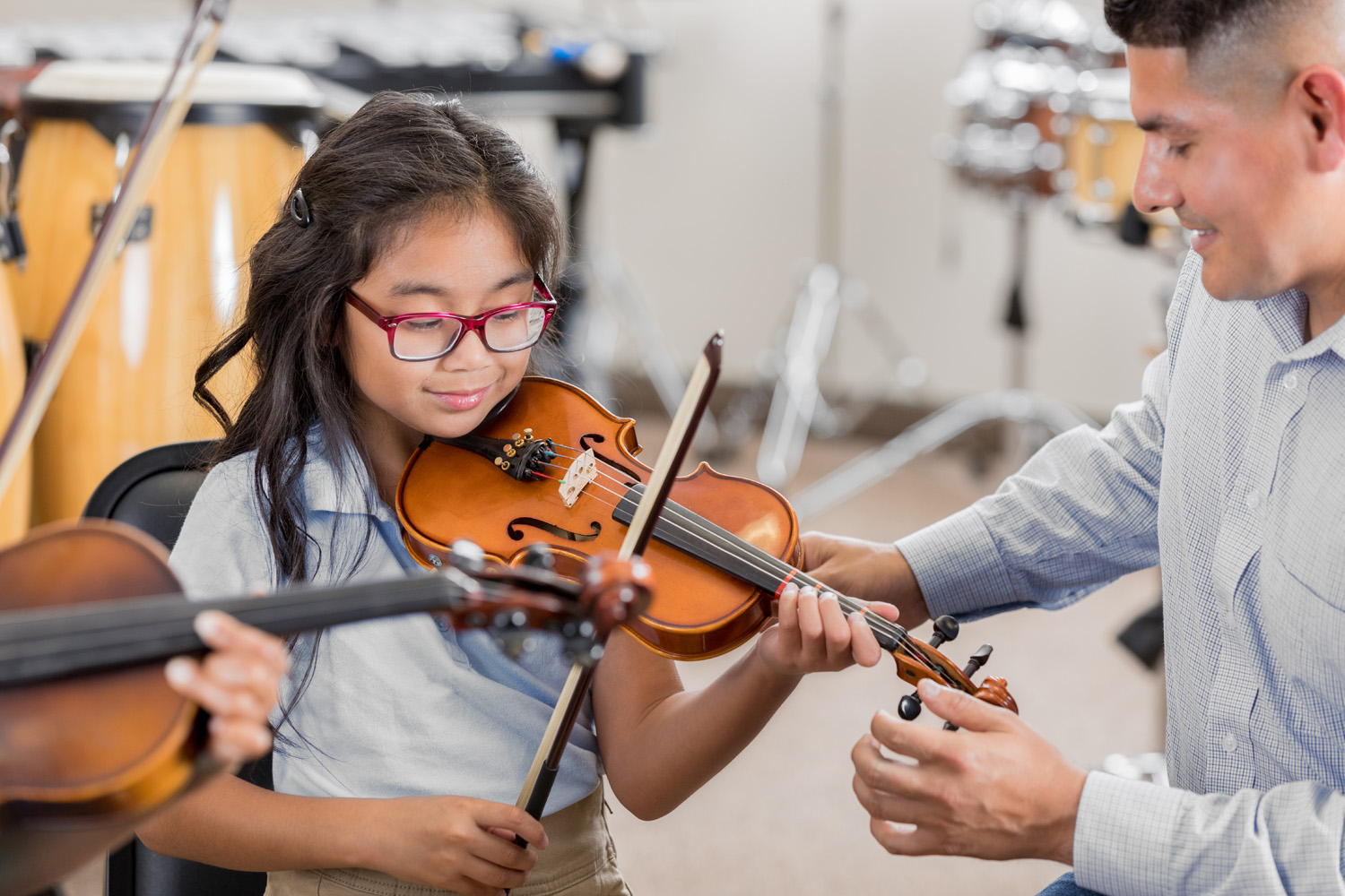 Photo of a child being taught violin in a school classroom