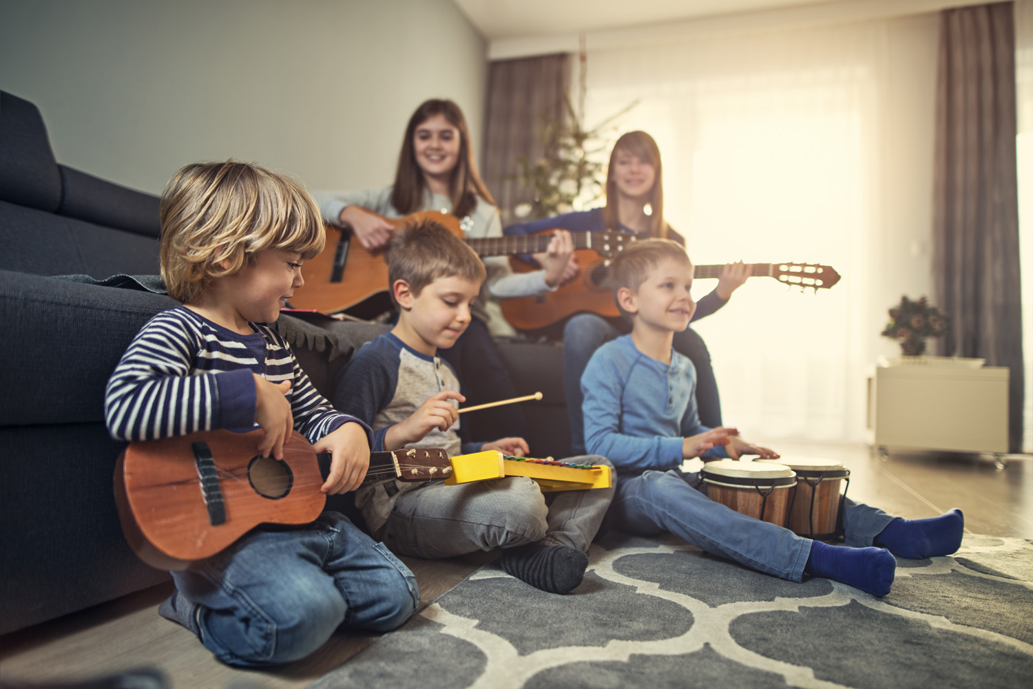Photo of young playing musical instruments in front of the Christmas tree