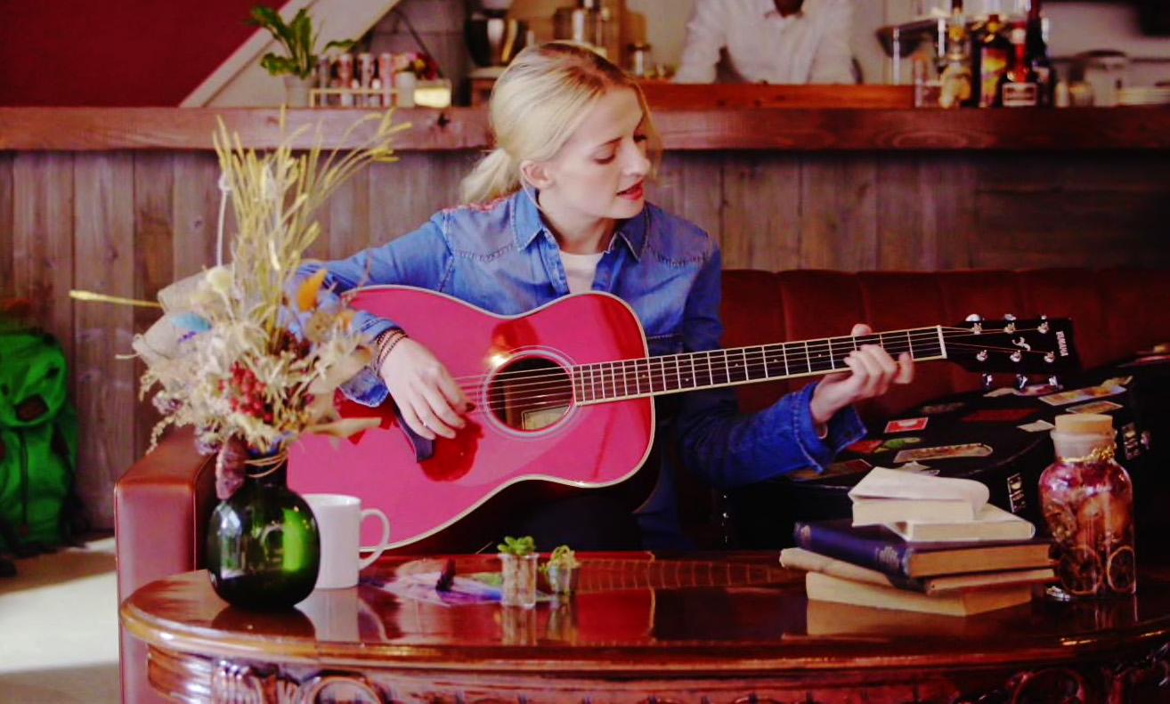 A woman playing a TransAcoustic guitar in a coffee shop