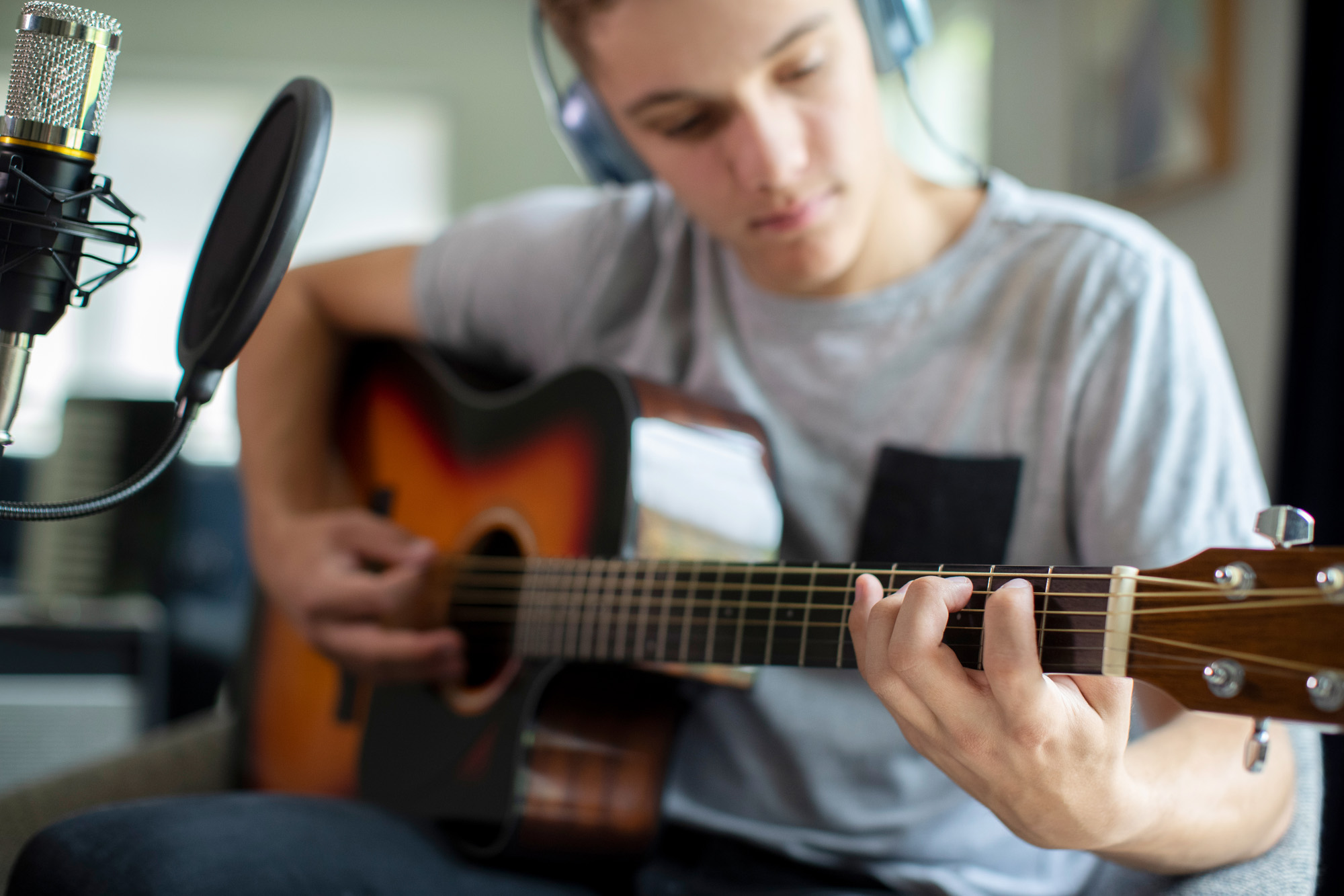 Teenage boy recording his guitar playing and vocals
